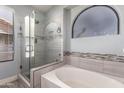 Bathroom with a soaking tub and glass shower, featuring modern fixtures and tile surround at 18643 N 73Rd Ave, Glendale, AZ 85308