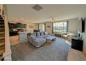 Open-concept living room flows into the kitchen, featuring plush carpeting and a comfortable gray sofa at 22026 N 28Th Pl, Phoenix, AZ 85050
