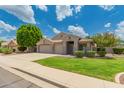 Charming single-story home showcasing a well-maintained lawn and mature trees beneath a vibrant blue sky at 2233 S Nielson St, Gilbert, AZ 85295