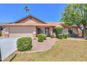 Charming single-story home featuring a well-manicured lawn, mature landscaping, and a two-car garage at 2322 E Dolphin Ave, Mesa, AZ 85204