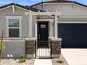 Welcoming front entrance with decorative stone accents, black metal gate, and covered porch at 37084 W Prado St, Maricopa, AZ 85138