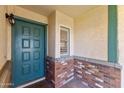Inviting entryway featuring a teal front door, brick accents, and a stylish outdoor light fixture at 4007 W Thunderbird Rd, Phoenix, AZ 85053