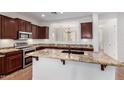 Modern kitchen featuring granite countertops, dark wood cabinets, stainless steel appliances and a central island at 7159 S Dodane Ct, Gilbert, AZ 85298