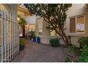 Inviting home entrance with a brick walkway, mature tree, and decorative gate at 1700 E Lakeside Dr # 12, Gilbert, AZ 85234