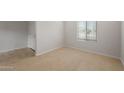 Bright bedroom with neutral carpet, white walls, a window with blinds, and a white door with chrome handle at 17782 W Getty Dr, Goodyear, AZ 85338