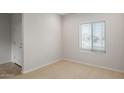 Bright bedroom with neutral carpet, white walls, a window with blinds, and a white door with chrome handle at 17782 W Getty Dr, Goodyear, AZ 85338