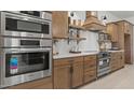 Modern kitchen featuring stainless steel appliances, including oven, microwave, and gas range, with wooden cabinetry at 42064 N Golden Trl, San Tan Valley, AZ 85140