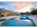 Luxurious backyard with pool, outdoor kitchen, built-in seating, and manicured lawn under a vibrant sunset at 6718 E Caron Dr, Paradise Valley, AZ 85253