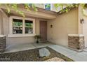 Inviting front entrance with a tan exterior, rock landscaping, and charming architectural details at 12217 W Planada Ln, Sun City, AZ 85373