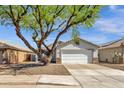 Single-story home featuring a two-car garage, stone accents, desert landscaping, and a large shade tree at 1320 E Binner Dr, Chandler, AZ 85225