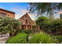 Charming stone cottage-style home with lush landscaping and a welcoming, idyllic facade at sunset at 27050 N 103Rd St, Scottsdale, AZ 85262