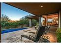 Relaxing covered patio overlooking a pool and desert landscaping, with comfortable seating and dining area at 39541 N 107Th Way, Scottsdale, AZ 85262