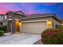 Home with a two-car garage, stone accents, and a blooming bush in the front yard at 5752 N 109Th Ave, Phoenix, AZ 85037