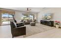 Bright living room featuring a ceiling fan, large windows with golf course views and modern decor at 15766 W Grand Point Ln, Surprise, AZ 85374