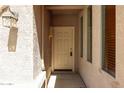 Well lit covered entry with sidelight window, lantern fixture and beige door at 17050 W Manchester Dr, Surprise, AZ 85374