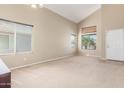 Bright living room with neutral carpet, vaulted ceilings, and large windows at 19933 N Emmerson Dr, Maricopa, AZ 85138