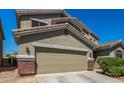 Home exterior featuring an attached garage with brickwork along the side, and xeriscaping in the front yard at 23848 W Grove St, Buckeye, AZ 85326