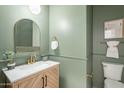 Stylish powder room with green walls, brass fixtures, and a framed mirror at 25925 N 53Rd Dr, Phoenix, AZ 85083