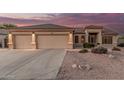 Charming home featuring a spacious three-car garage, tile roof, and desert landscaping at 8220 W Mariposa Grande Ln, Peoria, AZ 85383