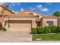 View of a single-story home with a two-car garage, terracotta tile roof, and well-maintained landscaping at 221 N Ironwood St, Gilbert, AZ 85234