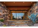Contemporary home's front entrance with glass doors, stone accents, and desert landscaping at 43105 N 102Nd St, Scottsdale, AZ 85262