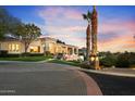 Elegant home with palm trees, manicured lawn, and a circular brick driveway at dusk at 6621 N Arizona Biltmore Cir, Phoenix, AZ 85016