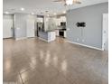 Open-concept living room with tile floors leading into a modern kitchen with white cabinets at 14154 W Voltaire St, Surprise, AZ 85379