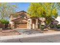 Attractive home with a two-car garage and covered entrance, complemented by mature desert trees at 15432 W Yucatan Dr, Surprise, AZ 85379