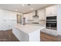 Modern kitchen boasts stainless steel appliances, white cabinets, a spacious island, and stylish backsplash at 17429 W Via Dona Rd, Surprise, AZ 85387
