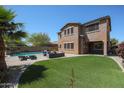 Spacious backyard with artificial grass, a patio with lounge seating, and a refreshing pool at 17981 W Agave Rd, Goodyear, AZ 85338