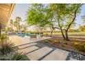 Expansive backyard featuring a swimming pool, lush greenery, patio seating, and mature trees at 20 W Canterbury Ln, Phoenix, AZ 85023