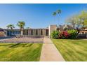 Stunning contemporary home featuring a lush green lawn, desert landscaping, and a striking modern design at 20 W Canterbury Ln, Phoenix, AZ 85023