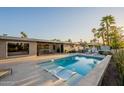 Inviting backyard featuring a sparkling pool, a jacuzzi, lounge chairs, and mature palm trees at 20 W Canterbury Ln, Phoenix, AZ 85023