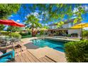 Beautiful backyard with a sparkling pool, mature palm trees, patio furniture and sunny yellow and red umbrellas at 2066 E Lockwood St, Mesa, AZ 85213