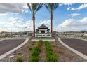 Welcoming entrance to Grove at Lehi featuring a guard house, palm trees, and manicured landscaping at 2517 E Presidio St, Mesa, AZ 85213