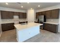 Spacious kitchen featuring a large island, stainless steel refrigerator, and dark wood cabinetry at 25348 W Bowker St, Buckeye, AZ 85326