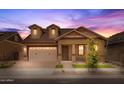Home exterior with a two-car garage, manicured landscaping, and a covered front porch at twilight at 4320 E Bernice St, Gilbert, AZ 85295