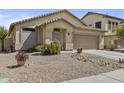 Well-maintained single-story home with a two-car garage and desert landscaping under a blue sky at 44284 W Buckhorn Trl, Maricopa, AZ 85138