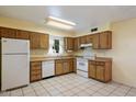 Well-lit kitchen featuring tile floors, white appliances, and wood cabinets at 4744 W Altadena Ave, Glendale, AZ 85304