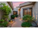 Inviting entrance with lush landscaping, rock features, and a well-lit pathway to the front door at 7425 E Gainey Ranch Rd # 13, Scottsdale, AZ 85258