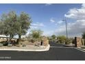 Gated community entrance featuring stone pillars, desert landscaping, and a tree on a sunny day at 11934 S 181St Ave, Goodyear, AZ 85338