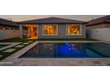 A backyard pool with LED lighting offers a refreshing escape, beautifully reflecting the home's exterior at dusk at 22849 E Marsh Rd, Queen Creek, AZ 85142
