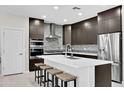 Modern kitchen features sleek dark cabinetry, stainless steel appliances, a large island, and stylish backsplash at 3549 W Magellan Dr, Anthem, AZ 85086