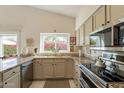 Bright kitchen featuring stone countertops, stainless steel appliances, and a large window overlooking the landscaped backyard at 13616 N 102Nd Pl, Scottsdale, AZ 85260