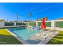 Beautiful pool featuring a waterfall, lounge chairs, red umbrella, and lush artificial turf at 8522 E Virginia Ave, Scottsdale, AZ 85257