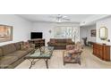 Cozy living room featuring ample seating, a glass coffee table, and natural light from shuttered windows at 21222 N Aurora Dr, Sun City West, AZ 85375