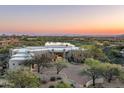Expansive aerial view of the luxurious estate overlooking a serene lake, golf course, and distant mountains at sunset at 41611 N 113Th Pl, Scottsdale, AZ 85262