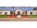 Welcoming entrance framed by palm trees and colorful floral displays leading to an arched doorway at 5220 N Casa Blanca Dr, Paradise Valley, AZ 85253