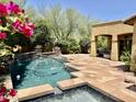 Beautiful backyard pool with water feature, stone decking and covered patio and landscaping at 9249 E Desert Arroyos St, Scottsdale, AZ 85255