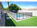 Backyard pool with safety fence surrounded by artificial turf, and a block wall at 520 E Appaloosa Rd, Gilbert, AZ 85296